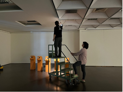 實習策展人們協助青年藝術家陳彥齊調整照射作品之燈光角度
